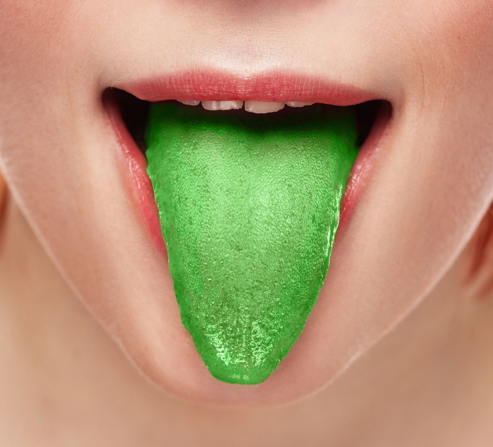 Woman with bad breath sticking out green tongue