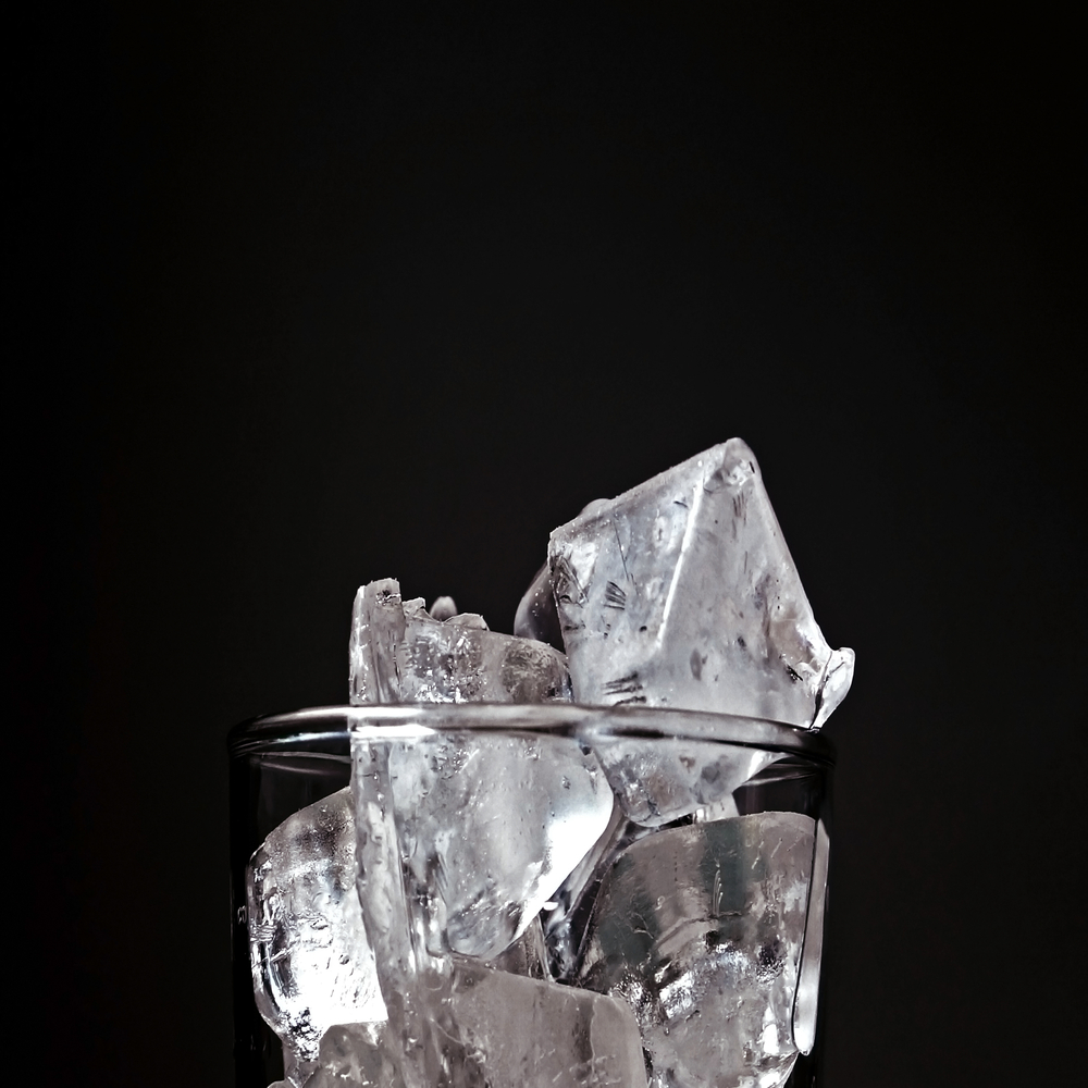 Top of clear glass full of ice stacked up past rim on black background