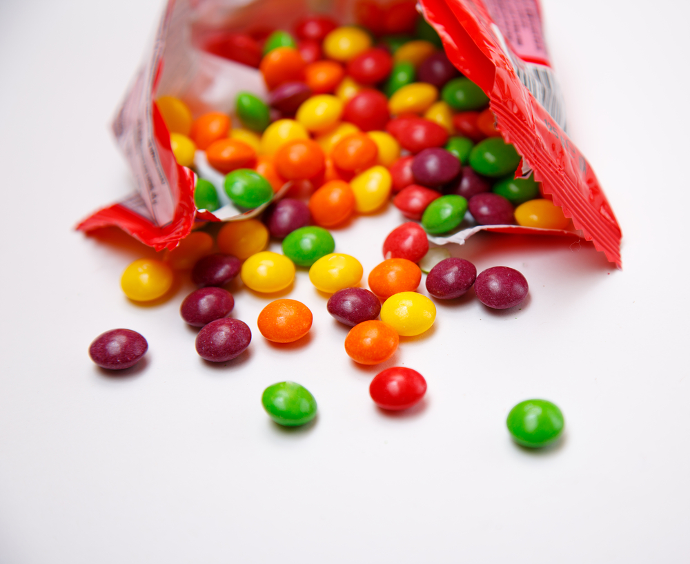 Open package of skittles on white background