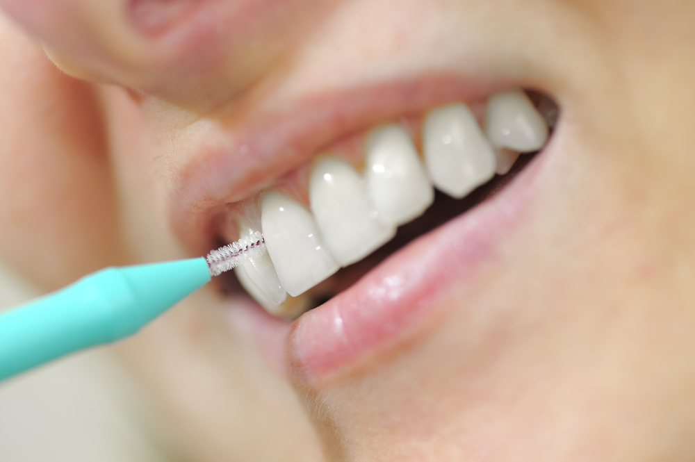 Woman using interdental flosser to clean teeth