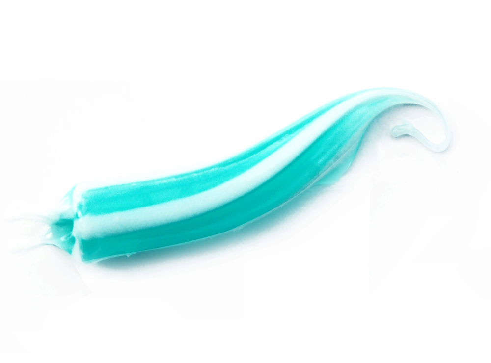 A squeeze of green and white toothpaste on white background