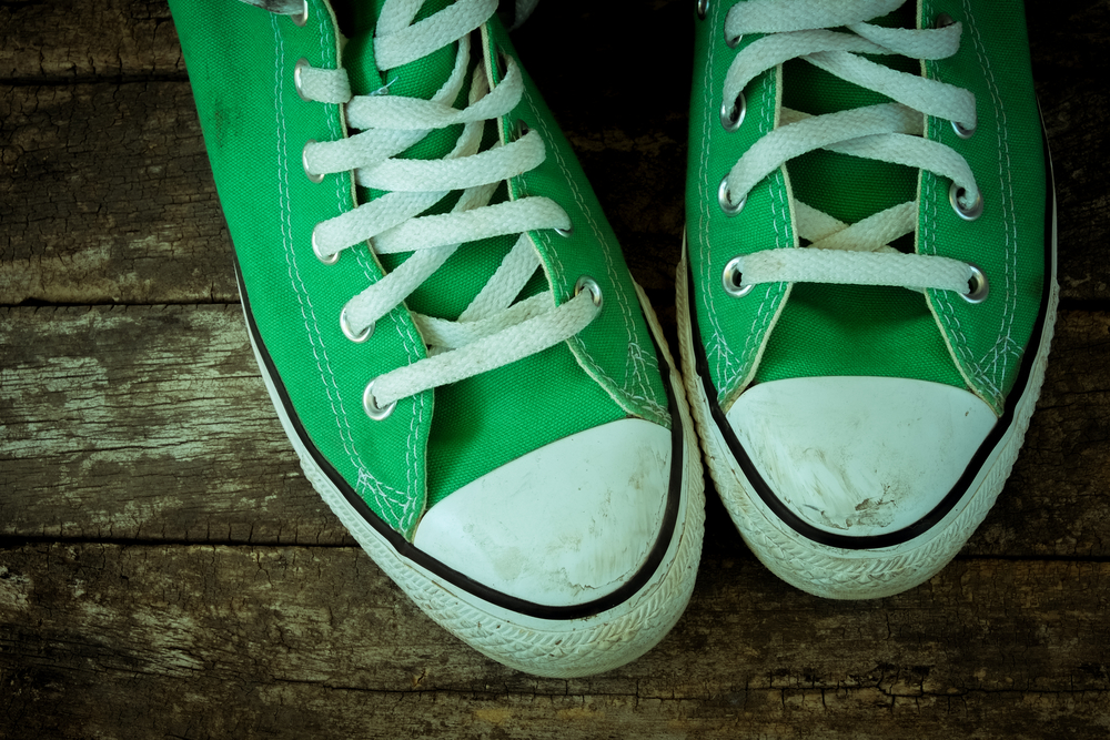 Dirty pair of green high top sneakers on wood plank background