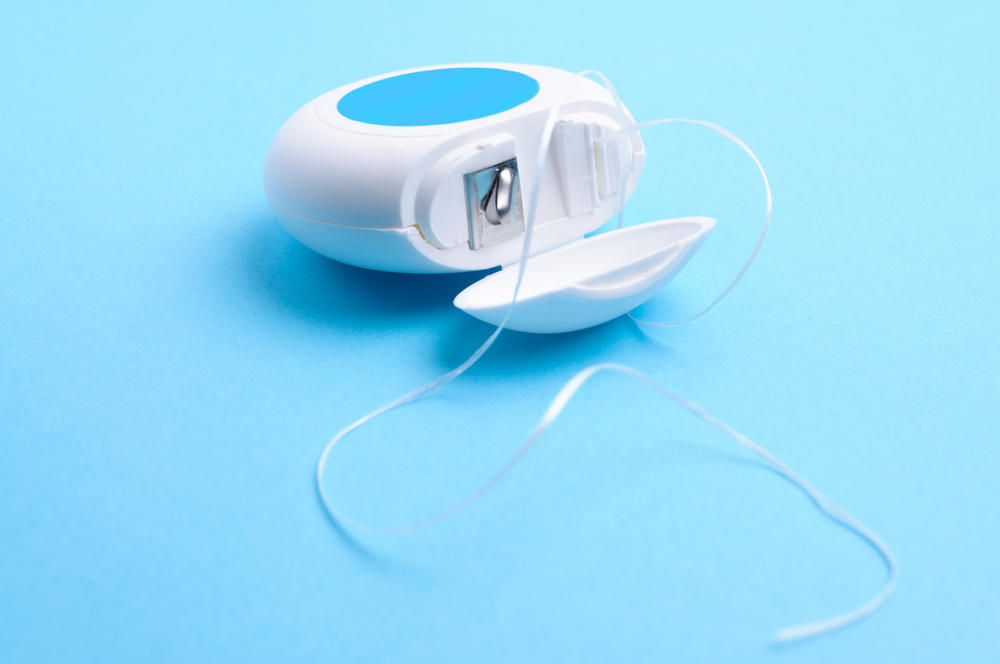 String floss flowing out of blue and white container on blue background