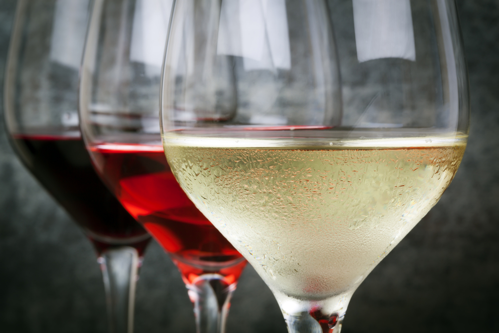 Row of 3 wine glasses with white, red, and dark red wine