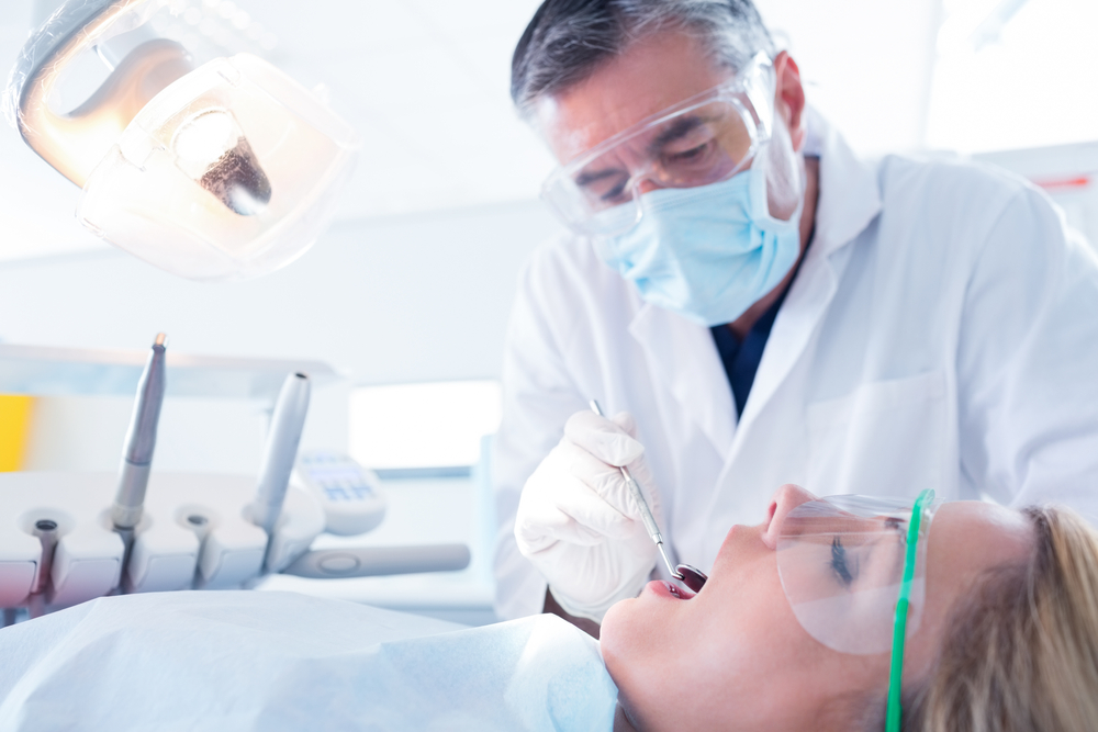 Dentist man examining woman patient's teeth in dental chair