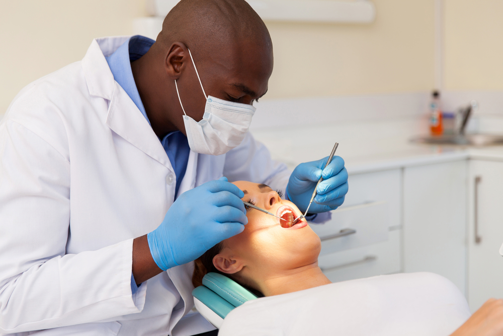 Dentist man examining woman patient's mouth with dental tools