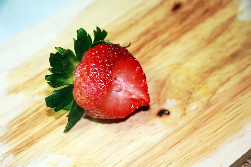 Top of strawberry with bit in it on wooden surface