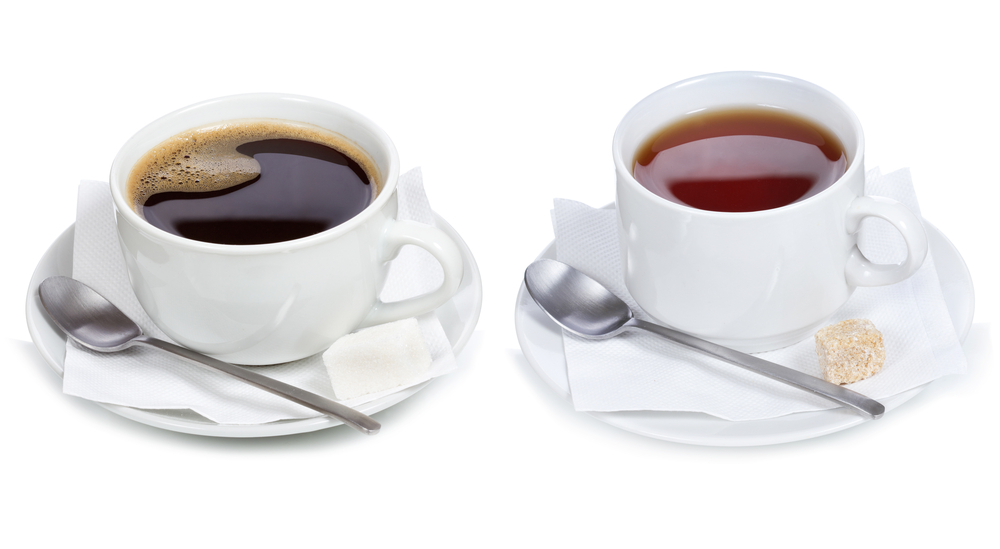 Cup of coffee on saucer with spoon and packet of sugar and cup of tea on saucer with spoon and sugar cube