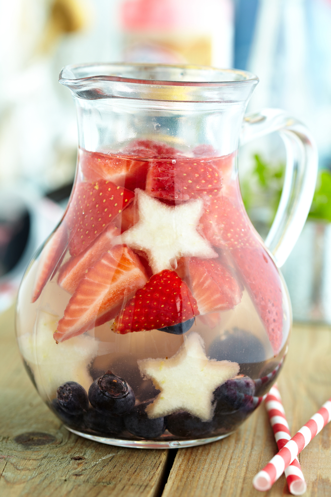 Glass pitcher of water with strawberries pineapple stars and blueberries patriotic