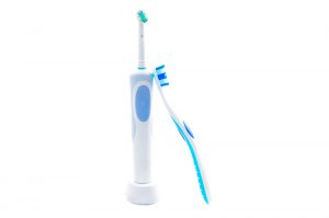 Manual toothbrush leaning against electric toothbrush
