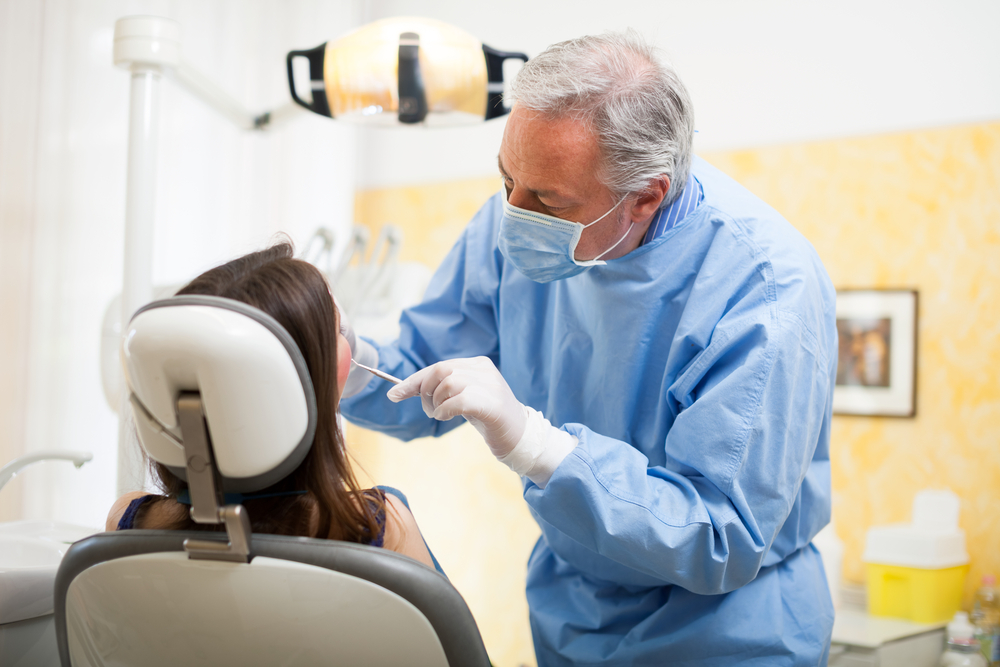 Dentist man looking into woman patient's mouth in dental chair