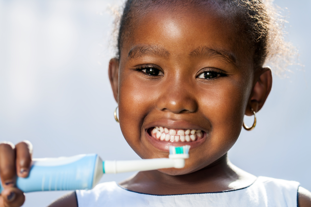 Little girl brushing her teeth with an electric toothbrush