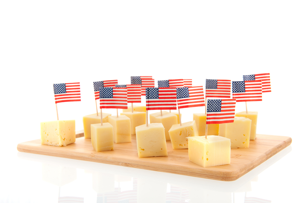 Cheese cubes with American flags on toothpicks on wood cutting board