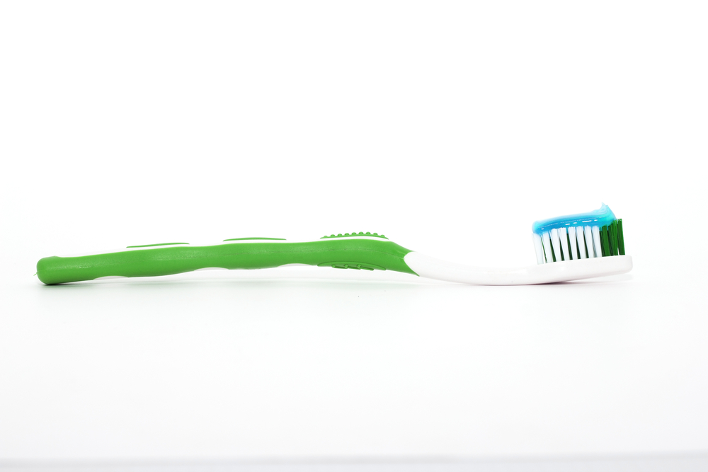 Green toothbrush with blue toothpaste on bristles