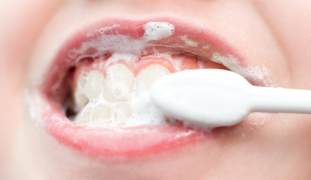 Close up of child's mouth brushing teeth with toothbrush and toothpaste