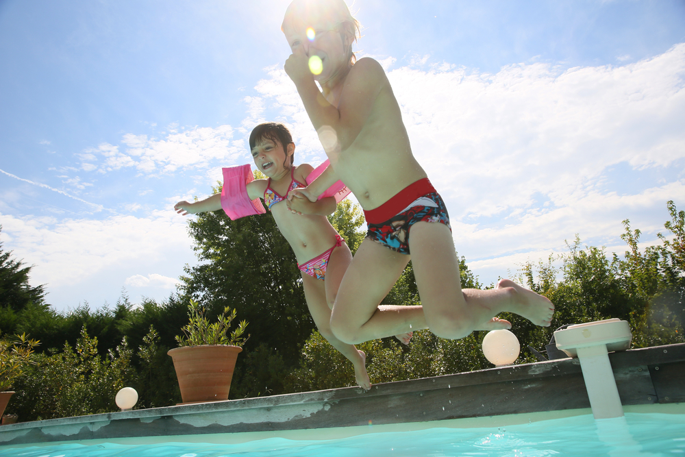 two young children jumping into a pool