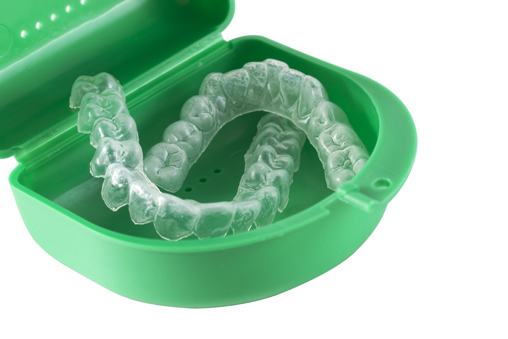 Clear dental Invisalign trays in green container case