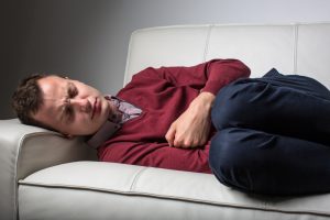 Young man suffering from severe belly pain, being cornered by the debilitating condition of celiac disease/Crohn's disease
