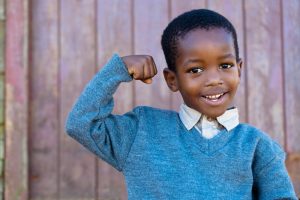 little smiling boy showing off is muscles