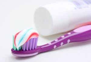 purple toothbrush and multicolored toothpaste