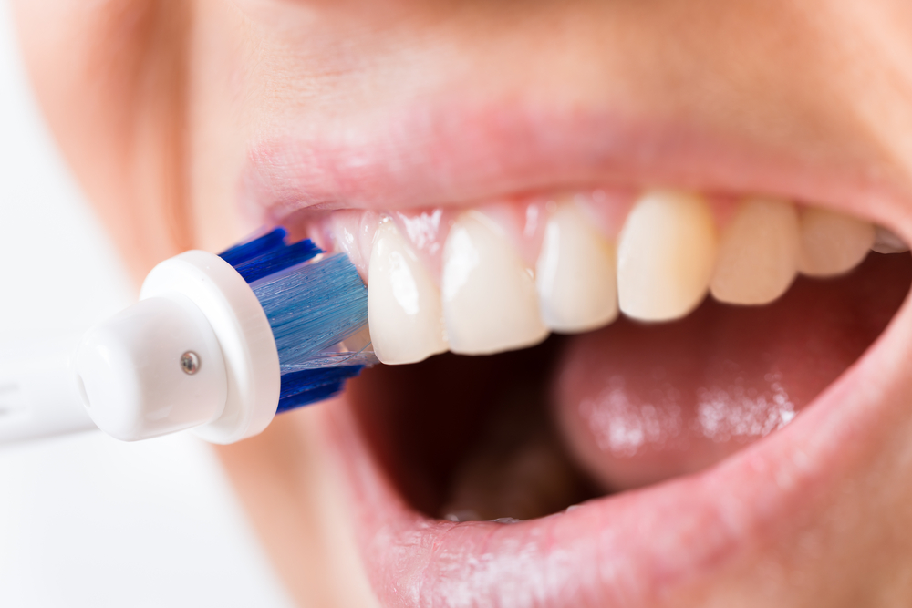 Close-up Of A Person Brushing Teeth Using Electric Toothbrush
