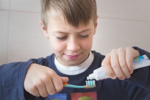 little boy puts toothpaste on his toothbrush