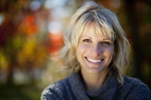 Woman smiling at the park (symbolizes a happy smile after a gum contouring procedure)