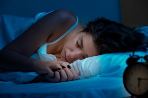 Woman sleeping in a bed in a dark bedroom -- deep sleep cycle
