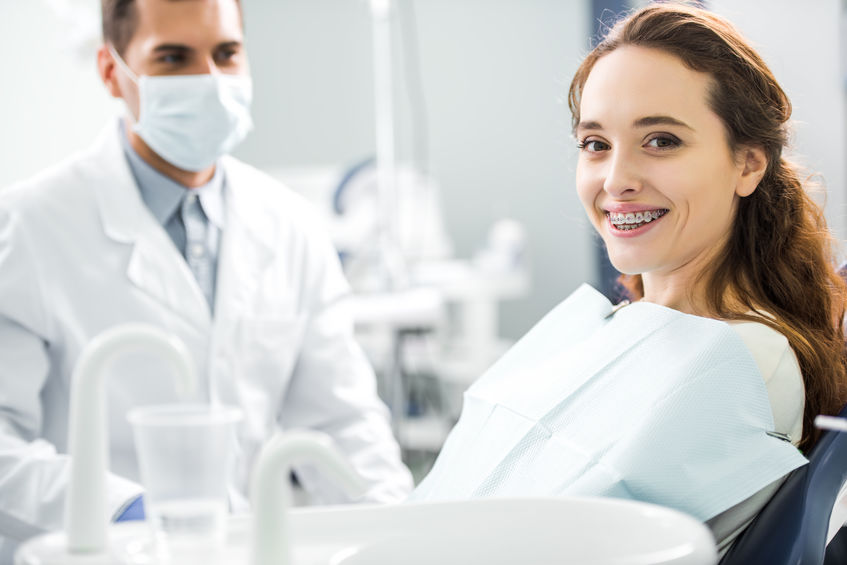 Picture of pleased woman sitting in a dental chair with braces
