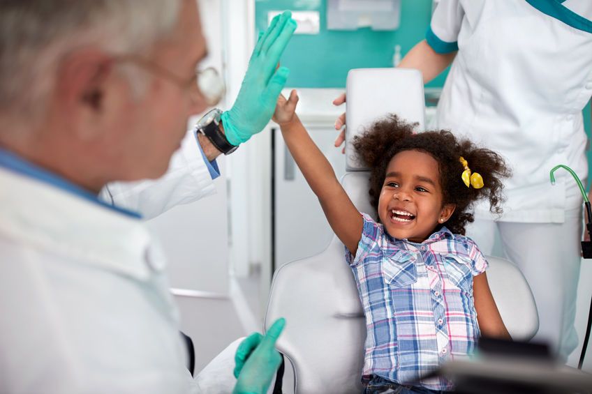 A dentist celebrates a young child's commitment to their oral health