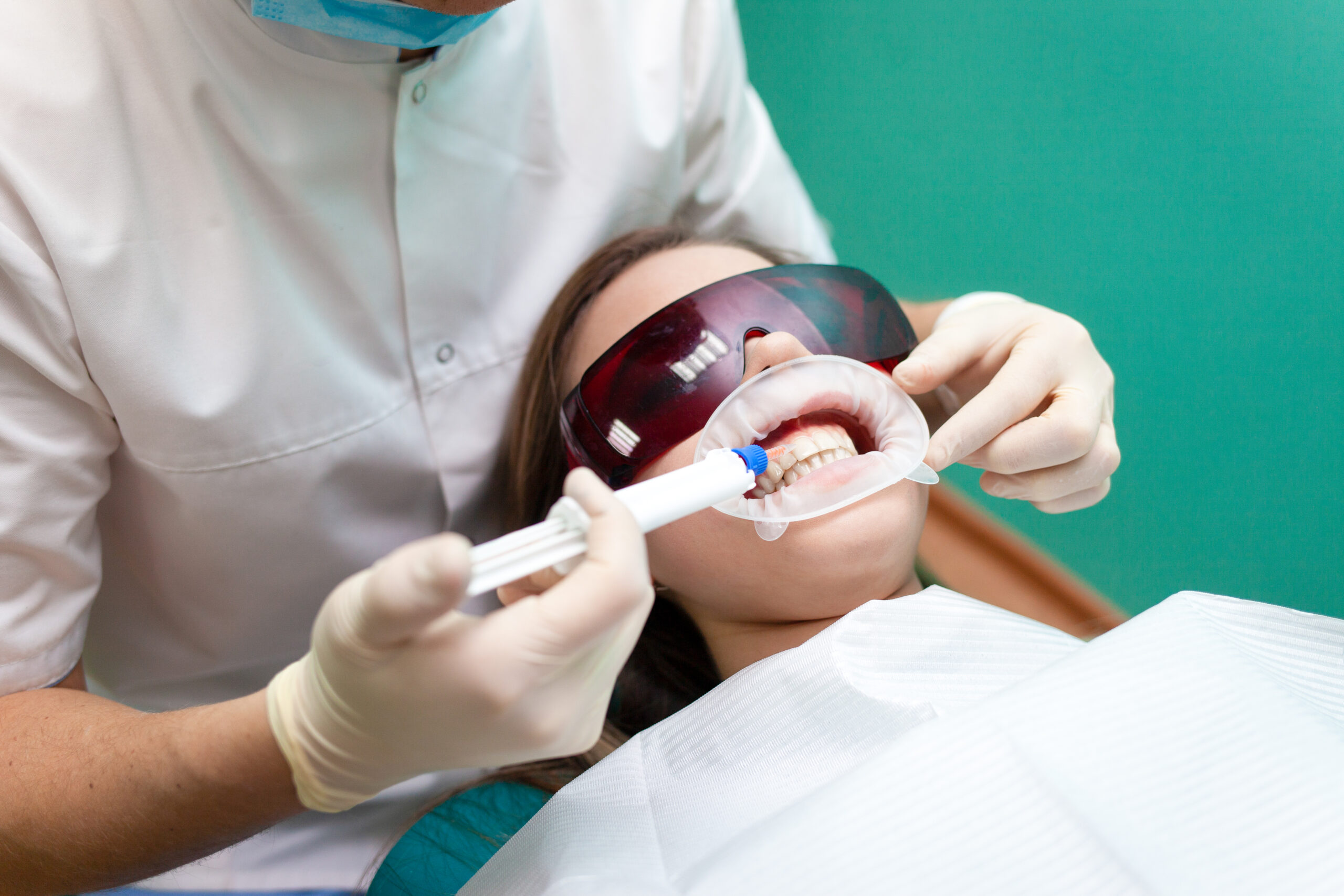 dentist applying a tooth whitening treatment to woman