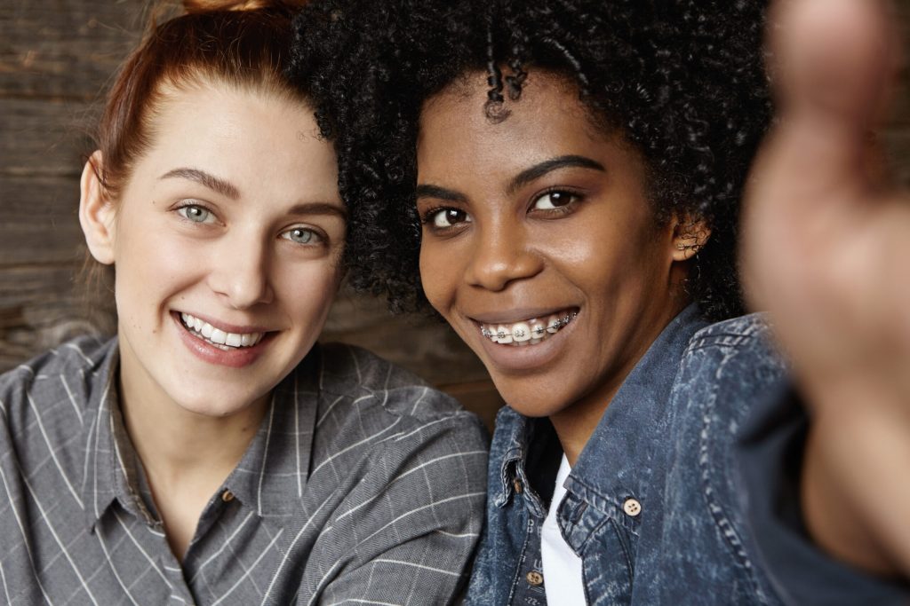 two women smiling at the camera one with adult braces