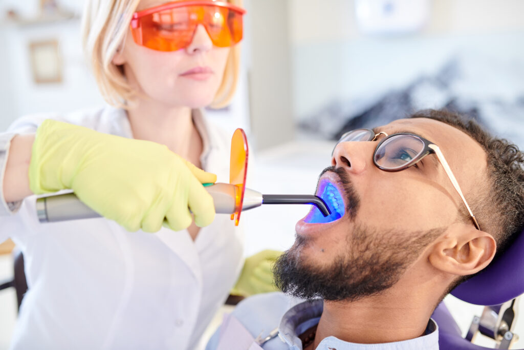 man undergoing teeth whitening procedure from dentist in office