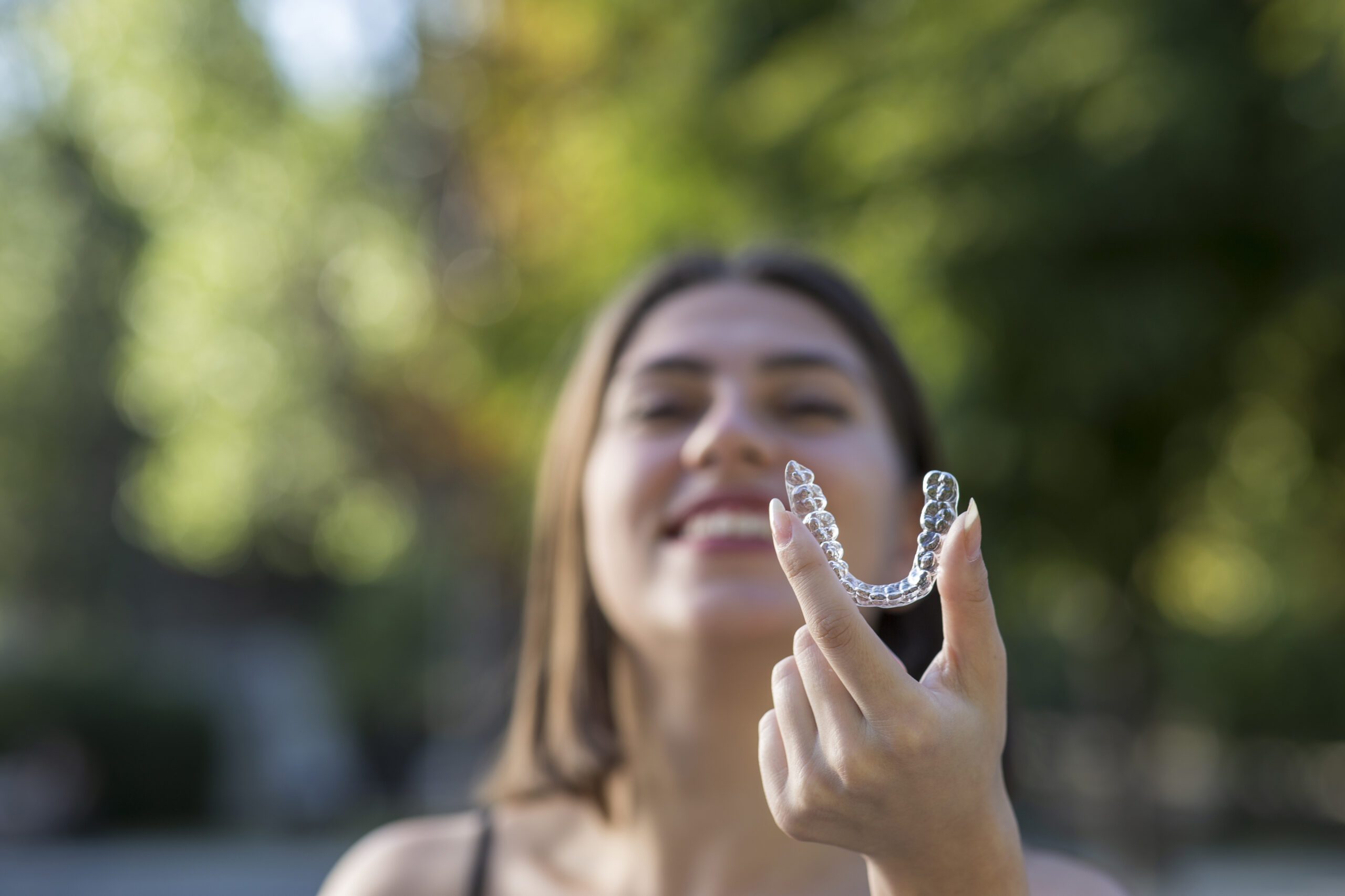 Woman smiling holding an invisalign