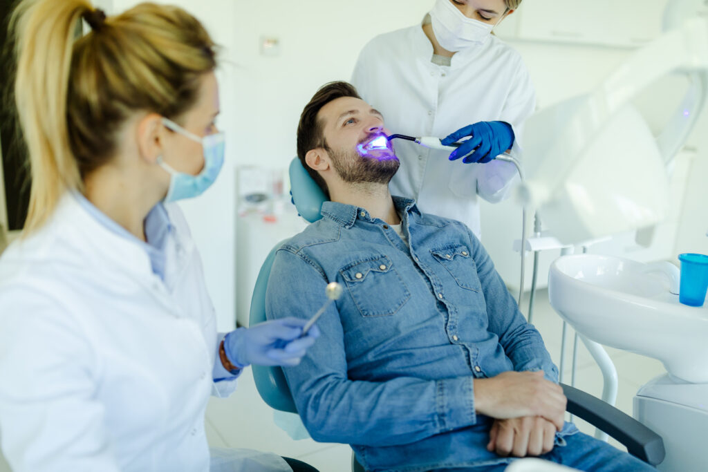 male patient in a dental chair receiving teeth whitening procedure