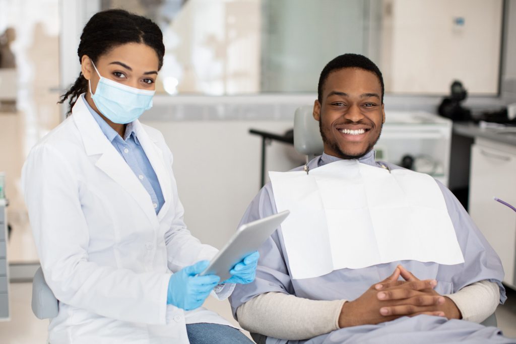 dentist and patient smiling while patient recieves care