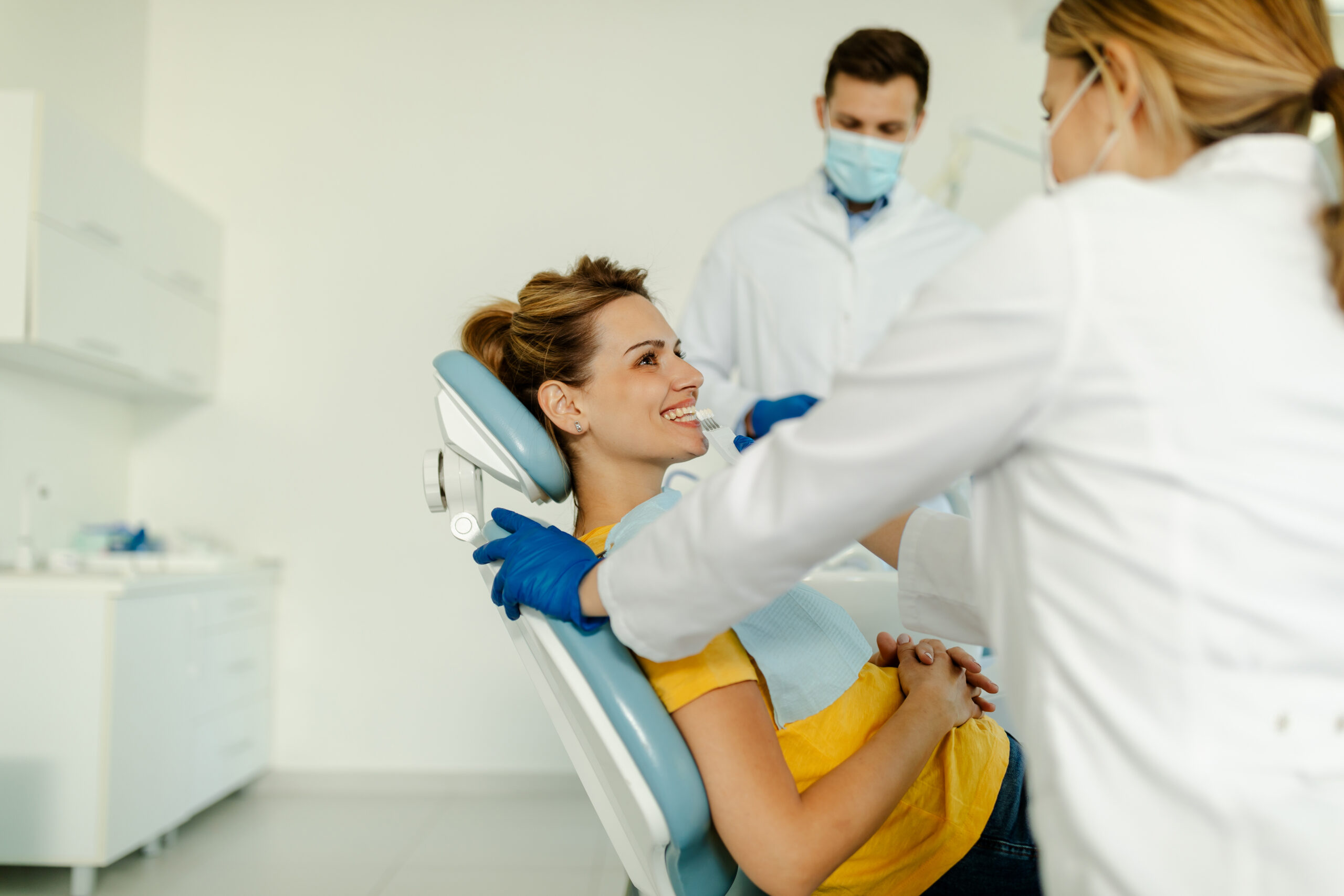 dentist talking to patient about dental care while patient reclines in dental chair