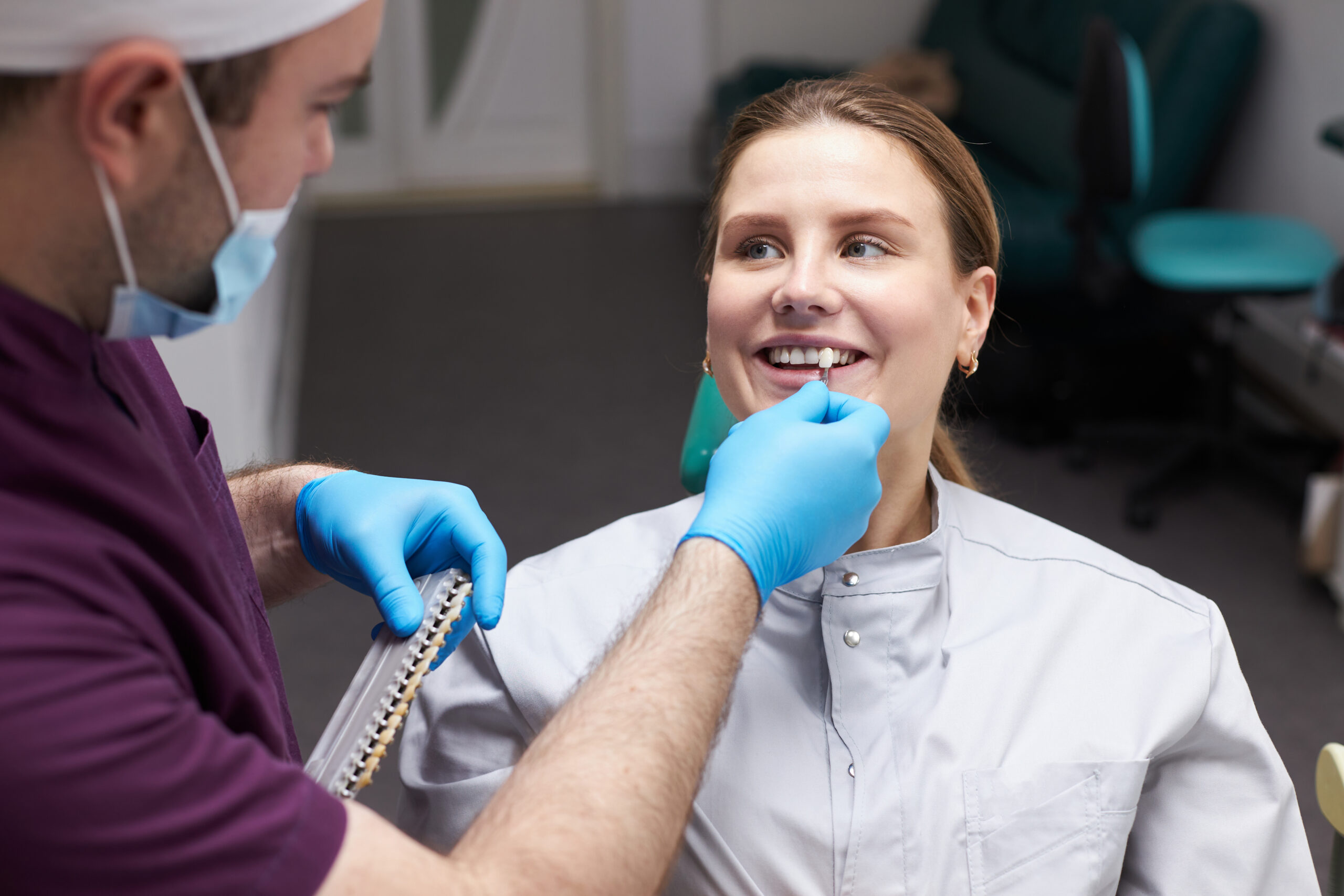 woman getting her veneer color matched by dentist