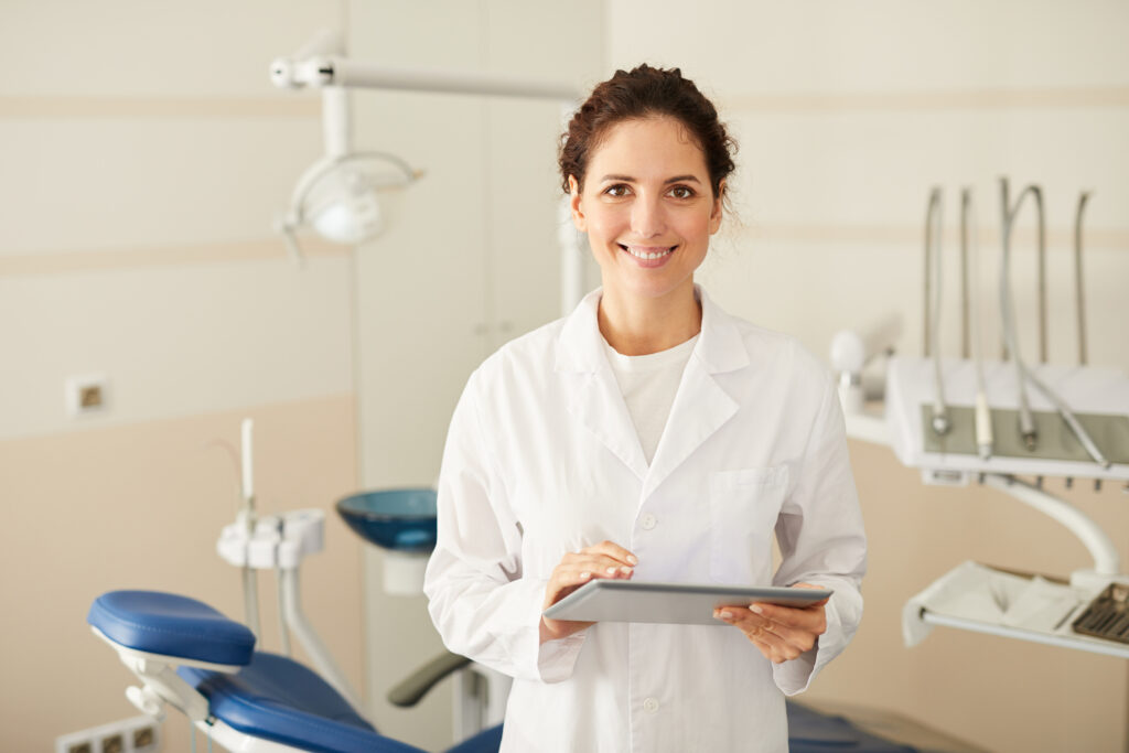 female dentist smiling at camera with clipboard