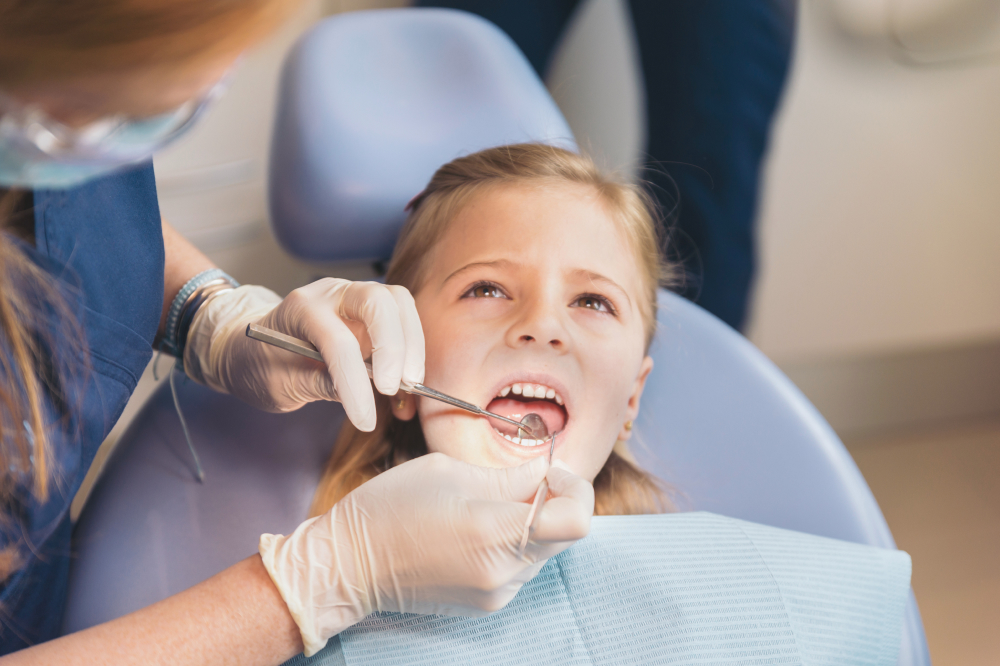 A young girl sits in a dental chair having a cavity treated
